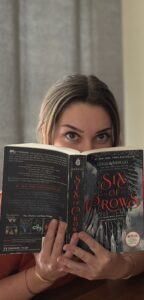Me peeking over Six of Crows Book.